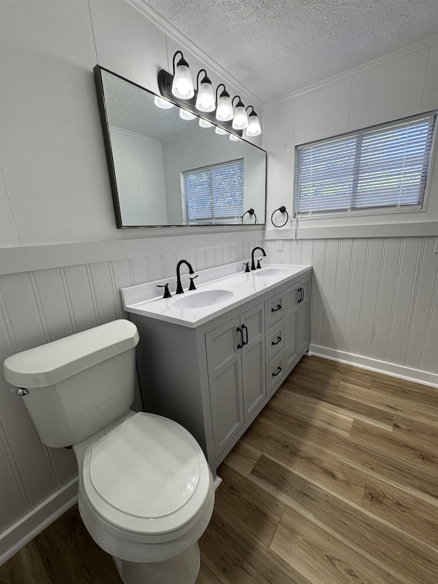 6250 Howe St, Groves, TX 77619 - bathroom with wood finished floors, a textured ceiling, a decorative wall, and double vanity