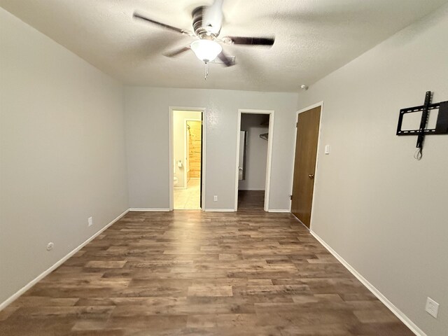 9410 Guy Cir, Beaumont, TX 77707 - unfurnished bedroom featuring wood finished floors, a walk in closet, ensuite bathroom, baseboards, and a textured ceiling