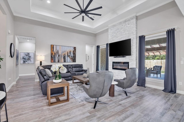 3435 Grey Hawk, Beaumont, TX 77707 - living area with wood finished floors, ceiling fan, a tray ceiling, a stone fireplace, and baseboards