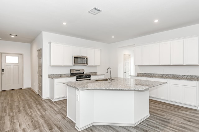 kitchen featuring white cabinetry, sink, appliances with stainless steel finishes, and an island with sink