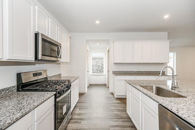 kitchen featuring white cabinets, light stone counters, sink, and appliances with stainless steel finishes