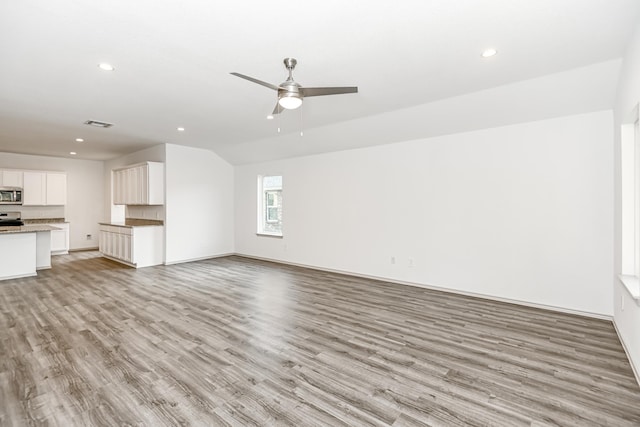 unfurnished living room with ceiling fan, vaulted ceiling, and light wood-type flooring