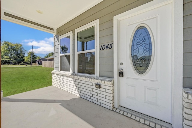 doorway to property with a porch and a lawn