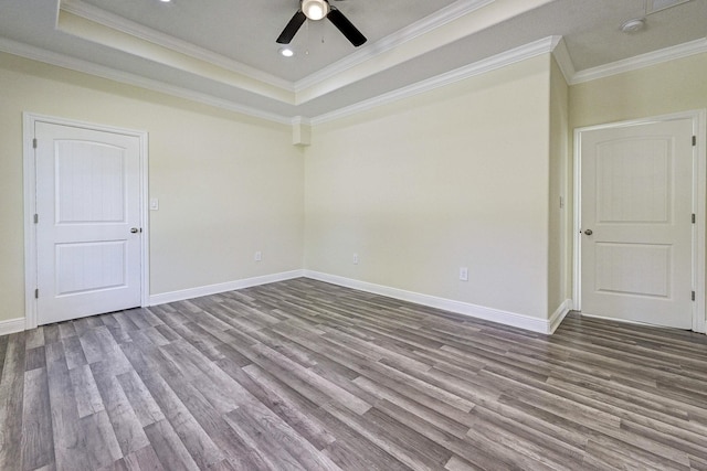 empty room featuring hardwood / wood-style flooring, ceiling fan, a raised ceiling, and crown molding