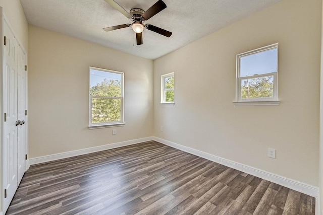 spare room with a textured ceiling, ceiling fan, and dark wood-type flooring