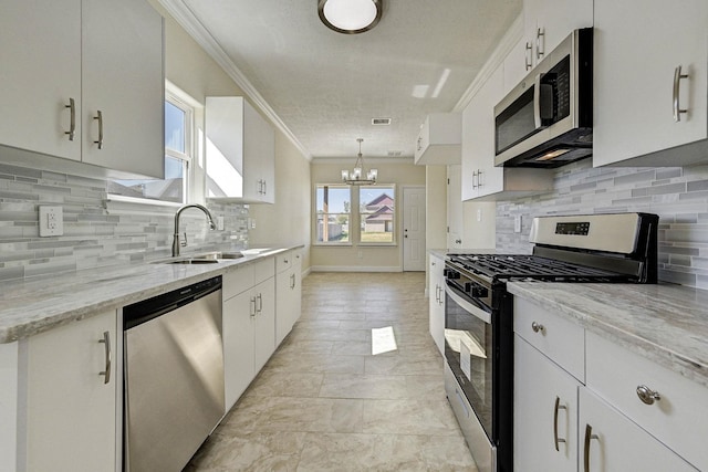 kitchen with white cabinets, sink, ornamental molding, decorative light fixtures, and stainless steel appliances