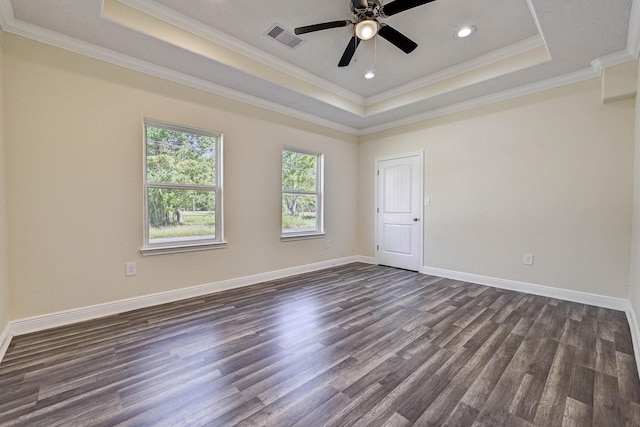 empty room featuring dark hardwood / wood-style flooring, a tray ceiling, ceiling fan, and crown molding