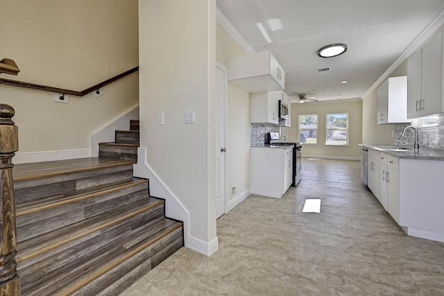 kitchen with stainless steel appliances, ceiling fan, crown molding, sink, and white cabinets