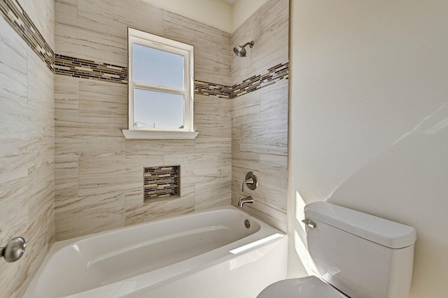 bathroom featuring tiled shower / bath combo and toilet