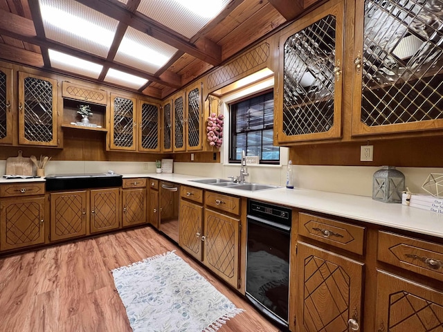 1205 Douglas St, Vidor, TX 77662 - kitchen with stainless steel dishwasher, stovetop, light countertops, light wood-type flooring, and brown cabinetry