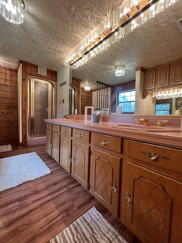 1205 Douglas St, Vidor, TX 77662 - kitchen featuring brown cabinetry, dark wood-style floors, wood walls, and a textured ceiling