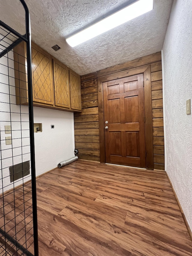 1205 Douglas St, Vidor, TX 77662 - laundry area featuring cabinet space, a textured ceiling, a textured wall, electric dryer hookup, and wood finished floors
