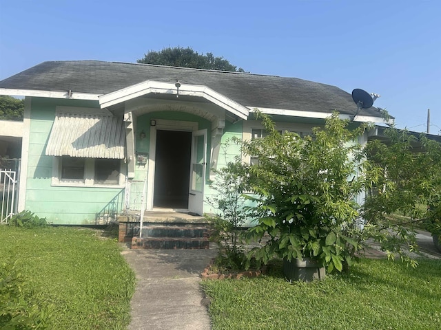 3924 7th St, Port Arthur, TX 77642 - view of exterior entry featuring a lawn and a shingled roof