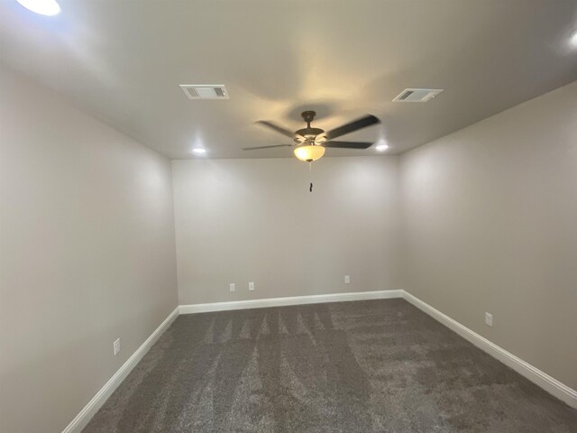 empty room featuring ceiling fan and dark colored carpet