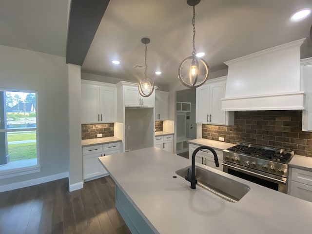 kitchen featuring pendant lighting, dark wood-type flooring, sink, stainless steel range, and white cabinetry