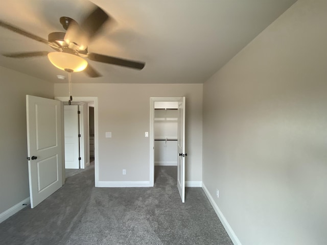 unfurnished bedroom with ceiling fan, a closet, a spacious closet, and dark colored carpet