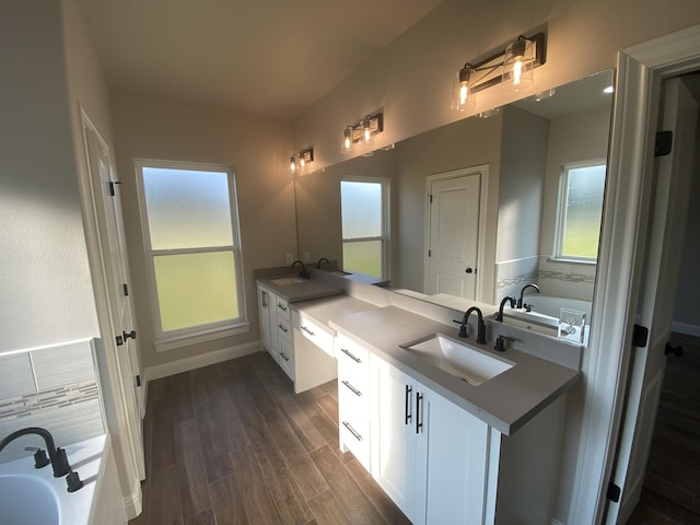 bathroom with vanity, wood-type flooring, and a tub to relax in