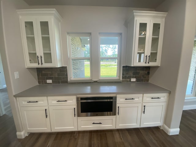 bar featuring white cabinets, oven, dark hardwood / wood-style flooring, and decorative backsplash