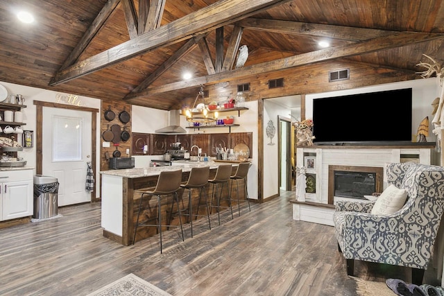 kitchen with lofted ceiling with beams, wall chimney range hood, and wooden ceiling