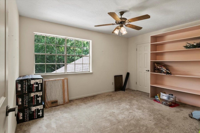 miscellaneous room featuring a textured ceiling, light colored carpet, and ceiling fan