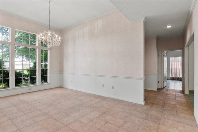 tiled spare room featuring ornamental molding, a wealth of natural light, and a chandelier