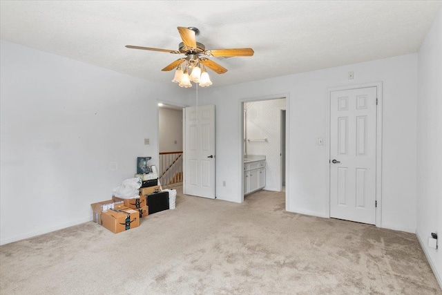 unfurnished bedroom with a textured ceiling, light colored carpet, ceiling fan, and ensuite bathroom