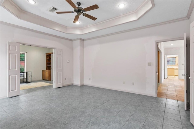 empty room featuring ceiling fan, a raised ceiling, light tile patterned floors, and crown molding