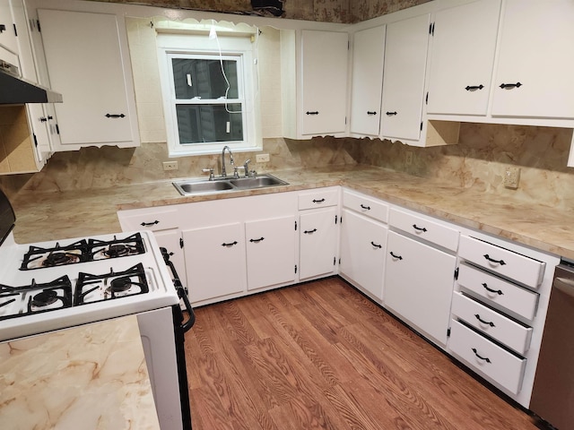 kitchen with white cabinetry, sink, backsplash, hardwood / wood-style flooring, and gas stove