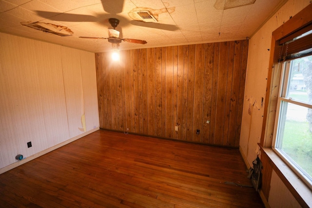 spare room featuring dark hardwood / wood-style flooring, a wealth of natural light, ceiling fan, and wood walls