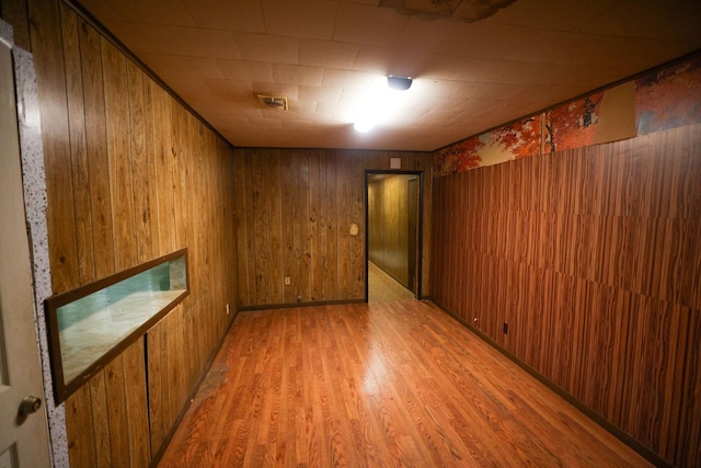 unfurnished room with hardwood / wood-style flooring and wooden walls