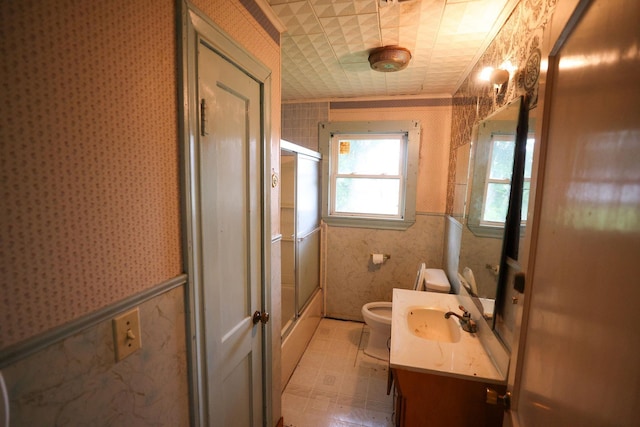 full bathroom with vanity, tile walls, shower / bath combination with glass door, and toilet