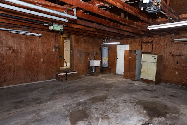 garage featuring sink, a garage door opener, gas water heater, and wood walls