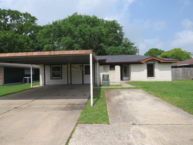 6219 16th St, Port Arthur, TX 77642 - view of front of house with driveway, central air condition unit, an attached carport, brick siding, and a front lawn