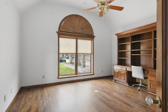 unfurnished office with dark hardwood / wood-style floors, ceiling fan, built in desk, and lofted ceiling