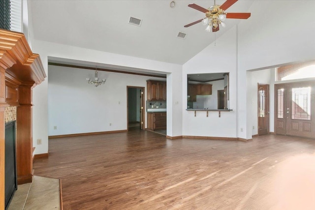 unfurnished living room featuring ceiling fan with notable chandelier, wood-type flooring, a fireplace, and high vaulted ceiling