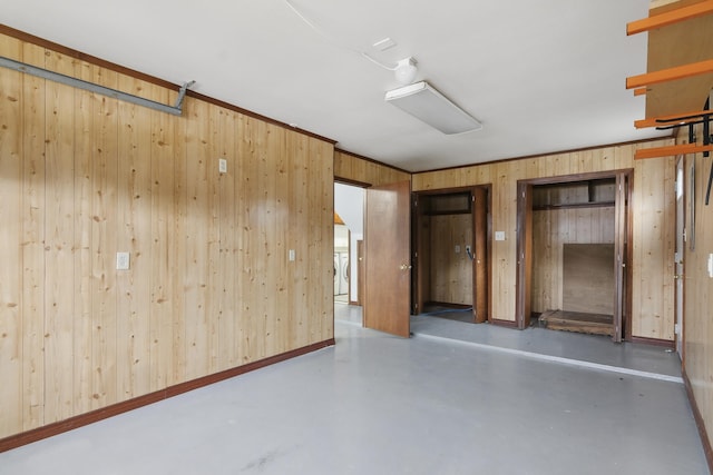 interior space featuring wood walls, concrete flooring, and ornamental molding