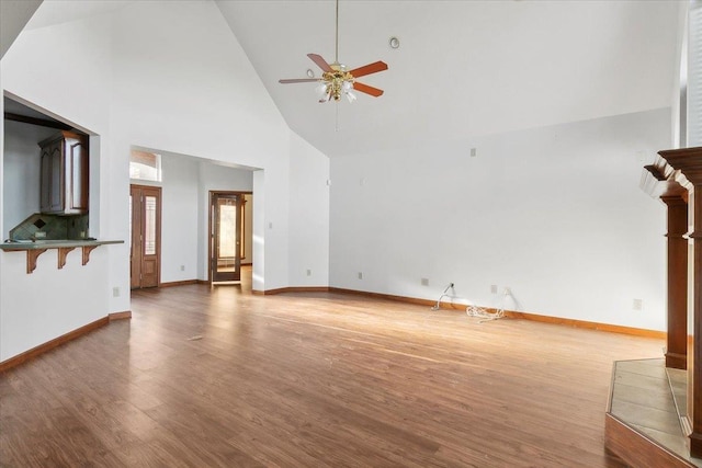 unfurnished living room with ceiling fan, high vaulted ceiling, and wood-type flooring