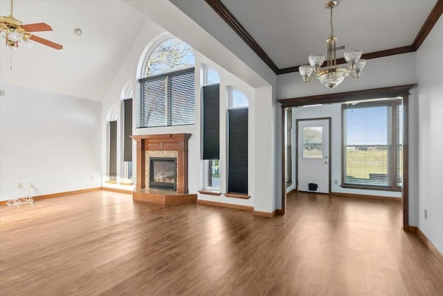 unfurnished living room with hardwood / wood-style floors, ceiling fan with notable chandelier, plenty of natural light, and crown molding