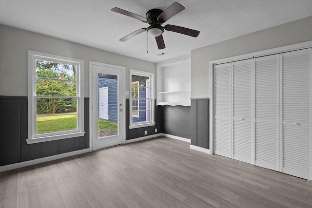 3015 Timberwood Ln, Beaumont, TX 77703 - unfurnished bedroom featuring wood finished floors, multiple windows, a closet, and a ceiling fan