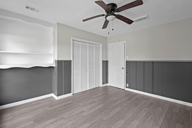 3015 Timberwood Ln, Beaumont, TX 77703 - unfurnished bedroom with wood finished floors, a closet, wainscoting, ceiling fan, and a textured ceiling