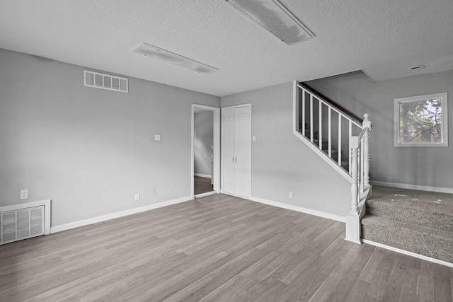 3015 Timberwood Ln, Beaumont, TX 77703 - unfurnished living room featuring a textured ceiling, wood finished floors, stairs, and baseboards