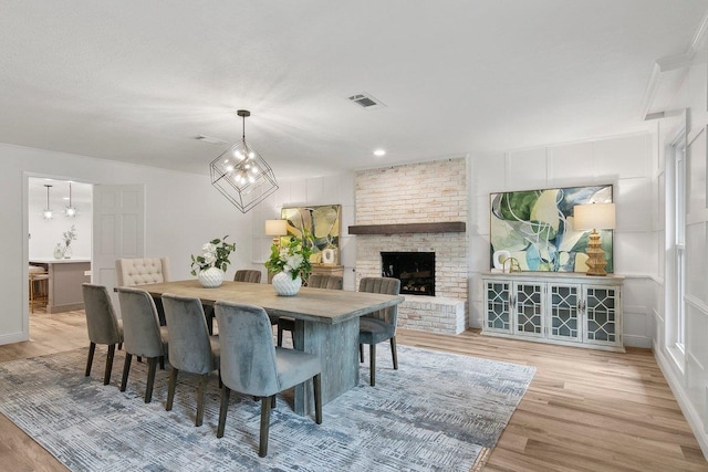 dining space with a fireplace, light hardwood / wood-style flooring, and a notable chandelier