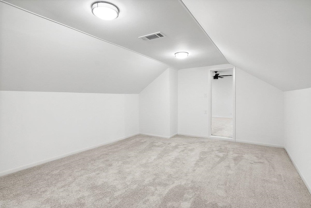 additional living space featuring light colored carpet and vaulted ceiling