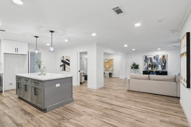 kitchen featuring white cabinetry, light wood-type flooring, gray cabinets, a kitchen island, and ornamental molding