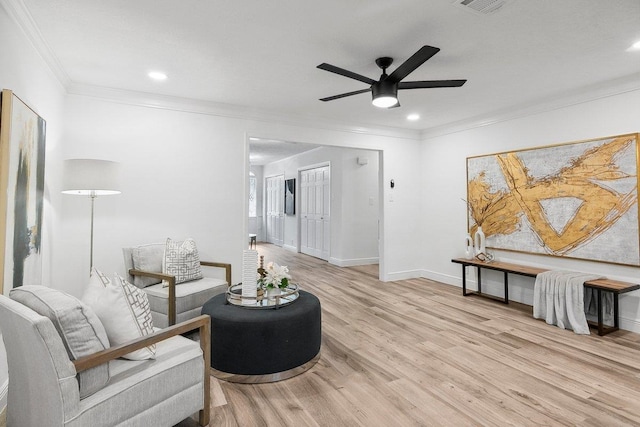 living room with light hardwood / wood-style flooring, ceiling fan, and ornamental molding