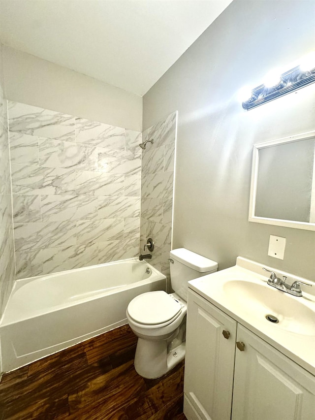 full bathroom featuring hardwood / wood-style flooring, vanity, tiled shower / bath combo, and toilet