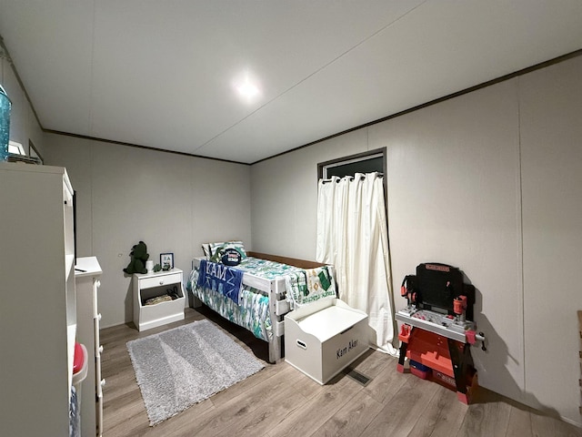 bedroom featuring crown molding and wood finished floors