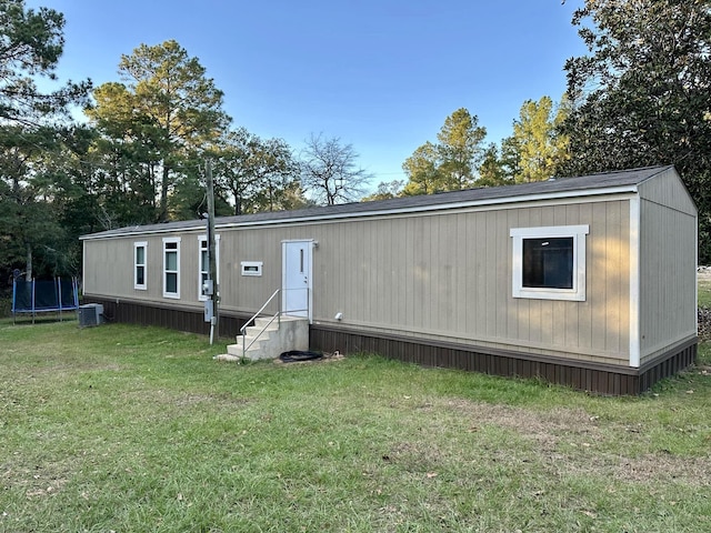 view of front of house featuring entry steps, a front yard, a trampoline, and central AC