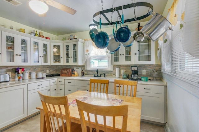 kitchen featuring decorative backsplash, sink, white cabinets, and light tile patterned floors