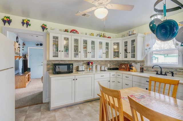 kitchen featuring tasteful backsplash, ceiling fan, sink, white refrigerator, and white cabinetry